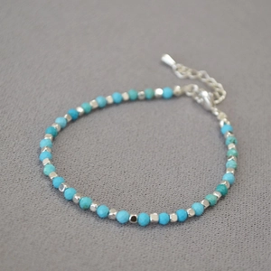 Macro shot of turquoise beaded bracelet with silver metal square beads and lobster clasp