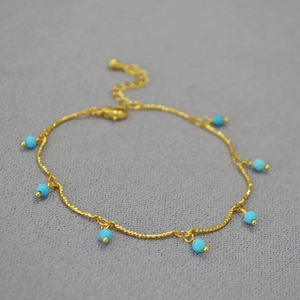 Close-up of gold-plated twisted chain necklace with seven turquoise round beads