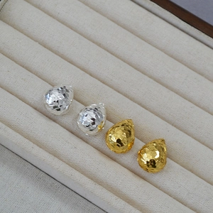 Detail of faceted water drop earrings in gold and silver finish on display