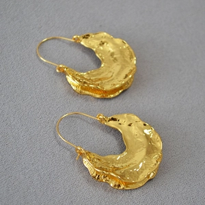 Detail of gold fan earrings with irregular lava texture and vintage hammered finish