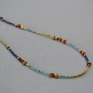 Close-up of handmade beaded necklace with turquoise, red agate and golden tube spacers