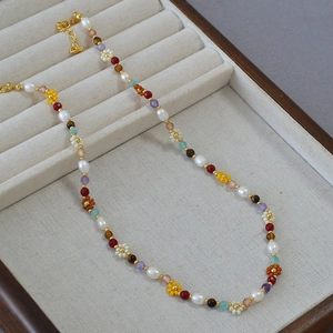Detail of colorful daisy bead necklace with freshwater pearls on a velvet tray