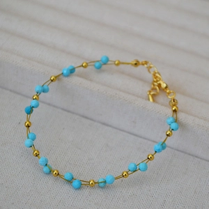 Close-up of gold beaded bracelet with blue lapis lazuli stones on a display box