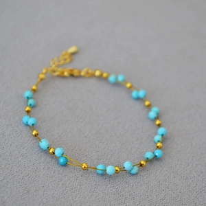 Detail of beaded gold chain bracelet with blue stones and adjustable lobster clasp