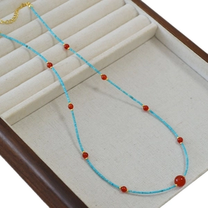 Minimalist necklace featuring turquoise tube beads and red agate accents with gold hardware