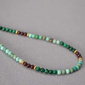 Détail macro de perles de malachite et turquoise avec entretoises dorées sur un collier