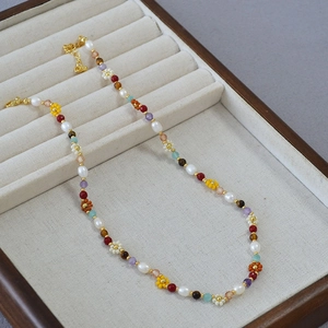 Detail of colorful beads and freshwater pearls necklace with woven flower elements