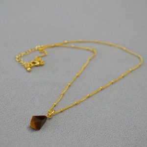 Detailed view of tiger eye pendant on a gold bead chain with adjustable lobster clasp