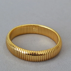 Macro detail of golden Tubogas wide elastic bracelet with polished spiral texture design