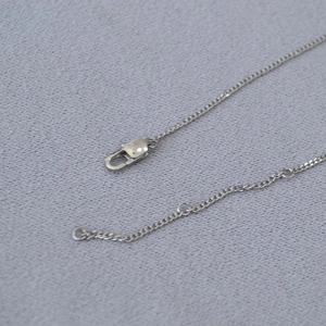 Detail of silver stainless steel Cuban chain featuring a lobster clasp and extension links