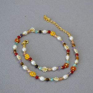 Daisy beaded necklace with freshwater pearls and colorful stones on a gray texture