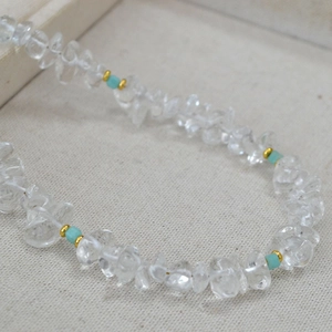 Detailed close-up of handmade white crystal bead necklace with turquoise stones and gold accents