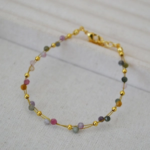 Close-up of minimalist layered gold wire bracelet with colorful lapis and gemstone beads
