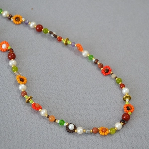 Détail d'un collier bohème fait main avec des perles et des breloques florales colorées