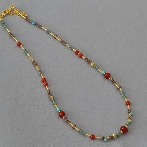 Detail of beaded necklace with red agate, turquoise accents and vintage style beads