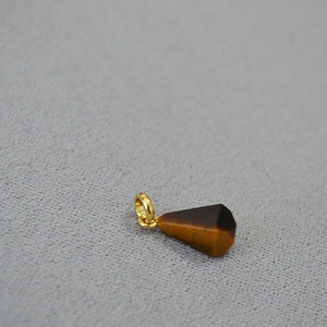 Macro detail of a conical tiger eye stone pendant with a gold plated ring connector