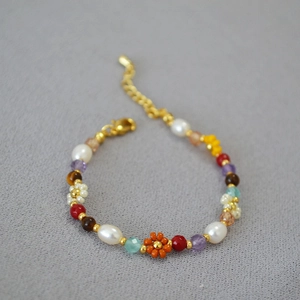 Detail view of handmade beaded necklace with freshwater pearls and daisy flower charm