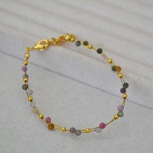 Detail of a minimalist gold wire double-layered bracelet with multicolored gemstone beads
