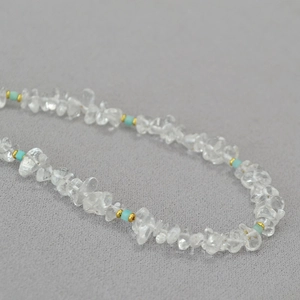 Macro detail of irregular clear quartz necklace with turquoise beads and gold accents