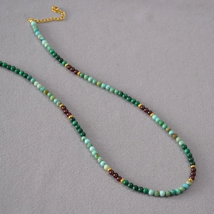 Détail du collier de perles turquoise, grenat et chaîne dorée ajustable