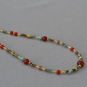Detail of bohemian red agate and turquoise beaded necklace with golden metal spacers