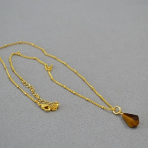 Close-up of geometric tiger eye pendant on gold brass chain with adjustable lobster clasp