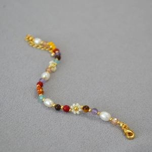 Detail of beaded necklace with freshwater pearls, colorful stones, and daisy flower charms