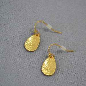 Macro view of gold leaf drop earrings with hammered texture and hook design