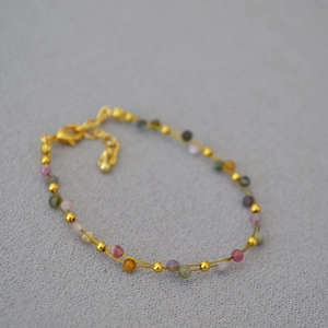 Detailed view of layered colorful gemstone beaded bracelet with gold lobster clasp and chain
