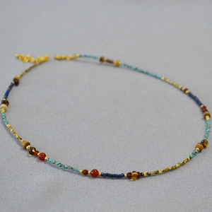 Detail of beaded necklace with turquoise, red agate, and gold metal spacer beads