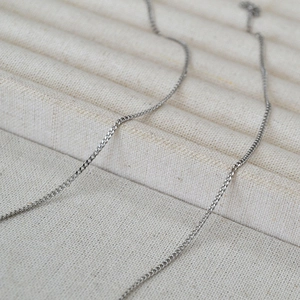 Detailed macro view of a silver stainless steel Cuban link chain with a matte finish