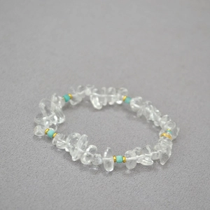 Macro detail of irregular white crystal beaded necklace with turquoise accents and gold rings