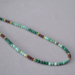 Détail macro de perles multicolores de malachite et turquoise avec accents dorés
