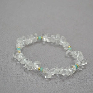 Close-up of irregular clear crystal and turquoise beads with gold accents on fabric