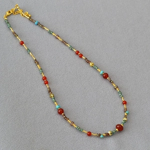 Detail of beaded necklace with red agate, turquoise, and gold spacer beads and clasp