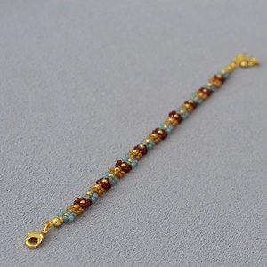 Detail of bohemian handmade beaded flower bracelet with gold beads and lobster clasp
