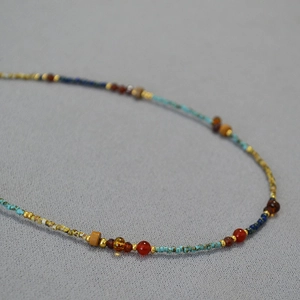 Macro detail of turquoise, lapis lazuli and red agate beaded necklace with gold spacers