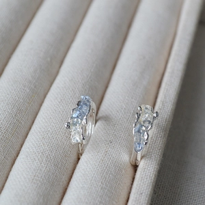 Detail of silver hoop earrings featuring hammered texture and inlaid blue crushed stones