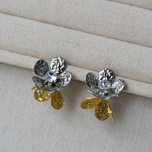Détail de boucles d'oreilles fleur bicolore plissée avec texture martelée et zircon