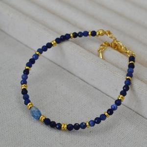 Dettaglio di perline sfaccettate in sodalite blu con distanziatori dorati e chiusura