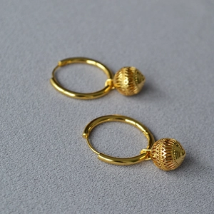 Gros plan de boucles d'oreilles lanternes vintage dorées sur un tissu gris texturé