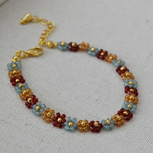 Macro shot of handmade beaded flower bracelet with blue and amber beads and gold clasp