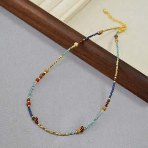 Close-up of bohemian thin beaded necklace with turquoise, agate, and gold accent beads
