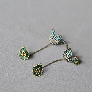 Detail of vintage bohemian earrings with ginger enamel flower and emerald tassels
