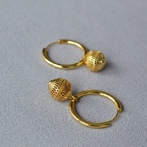 Détail de boucles d'oreilles lanternes rétro en laiton plaqué or avec texture ajourée