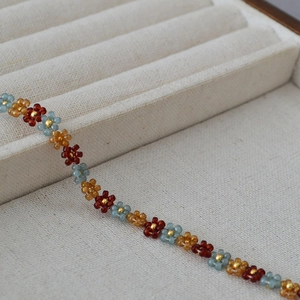 Detail of bohemian handmade beaded bracelet with colorful floral patterns and gold beads