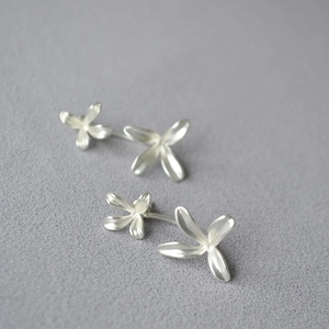 Detail of silver double floral earrings with matte finish on a textured background