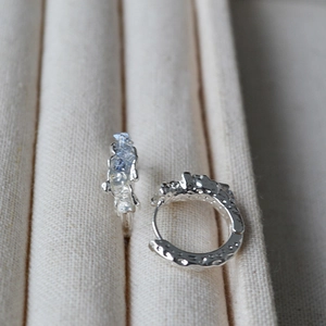Close-up of silver hammered texture hoop earrings with blue stones on a jewelry tray