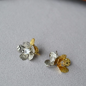 Détail de boucles d'oreilles fleurs bicolores avec texture martelée et centre en zircon