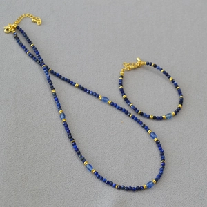 Dettaglio del set collana e bracciale con perle in sodalite blu e finiture dorate